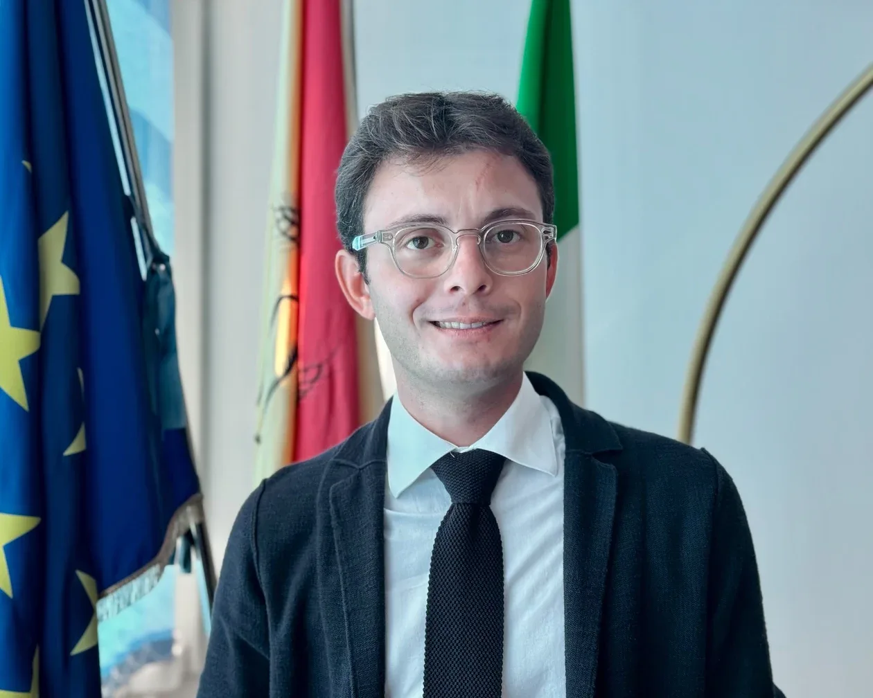 Luigi Genovese davanti alle bandiere italiana ed europea